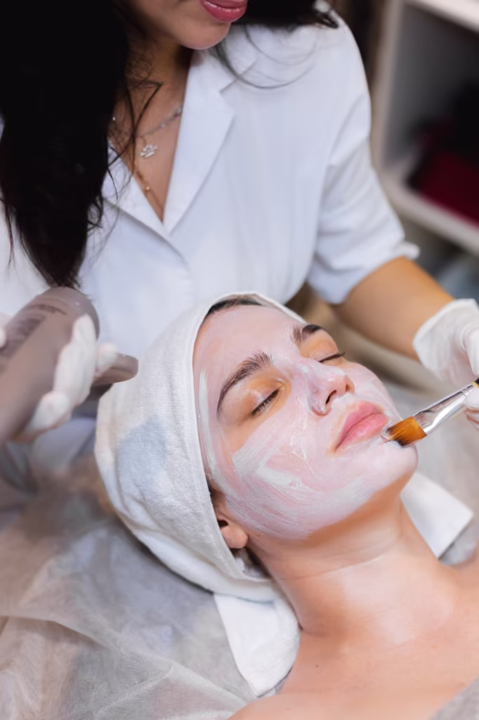 A professional esthetician applies a soothing facial mask with a brush to a relaxed client, highlighting the expert skincare treatments and luxurious spa services available at Spitale Laser Spa Salon.